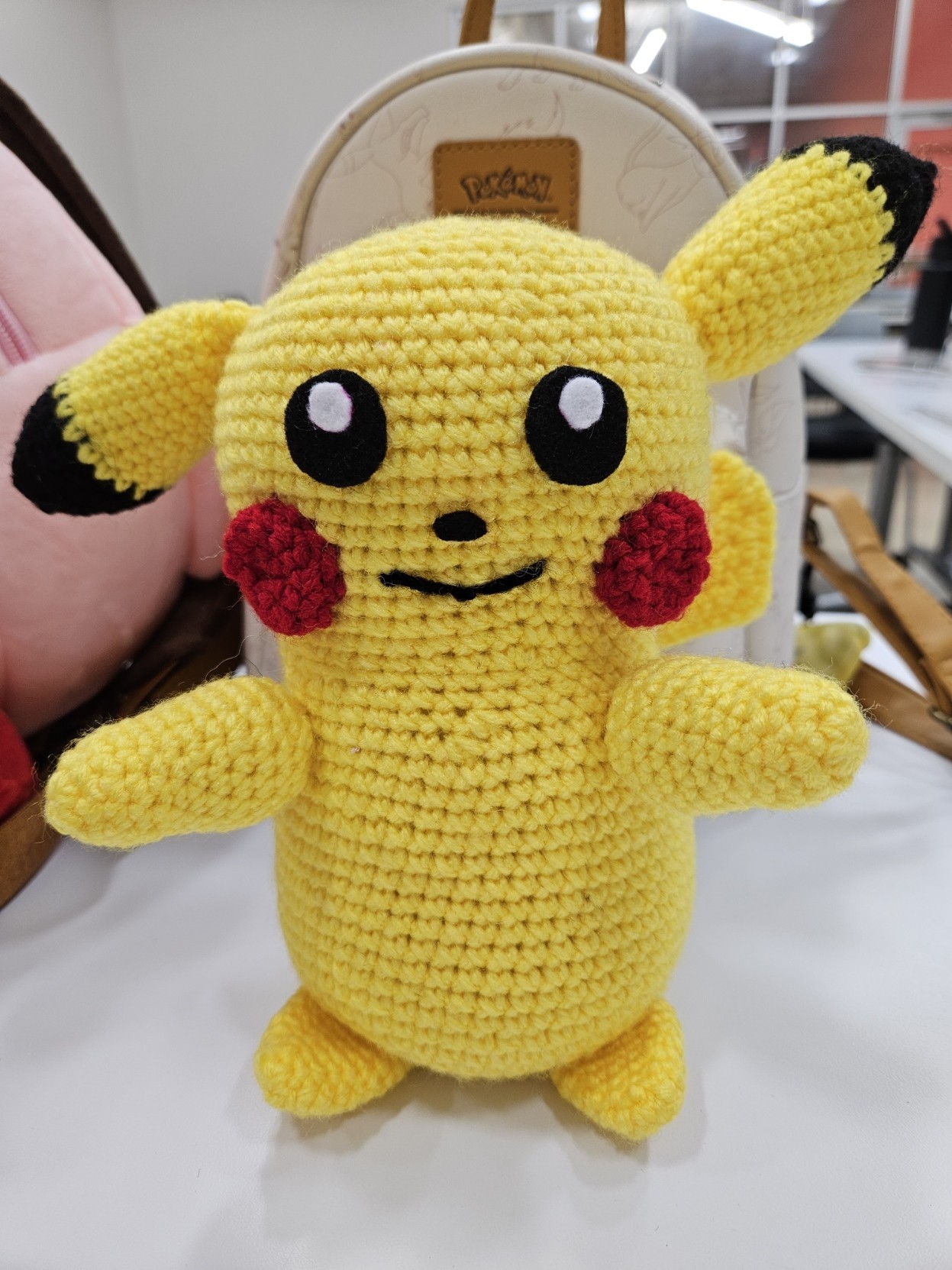 A crocheted Pikachu with felt eyes and nose and an embroidered mouth. Everything else is crocheted. One of his ears is bent.