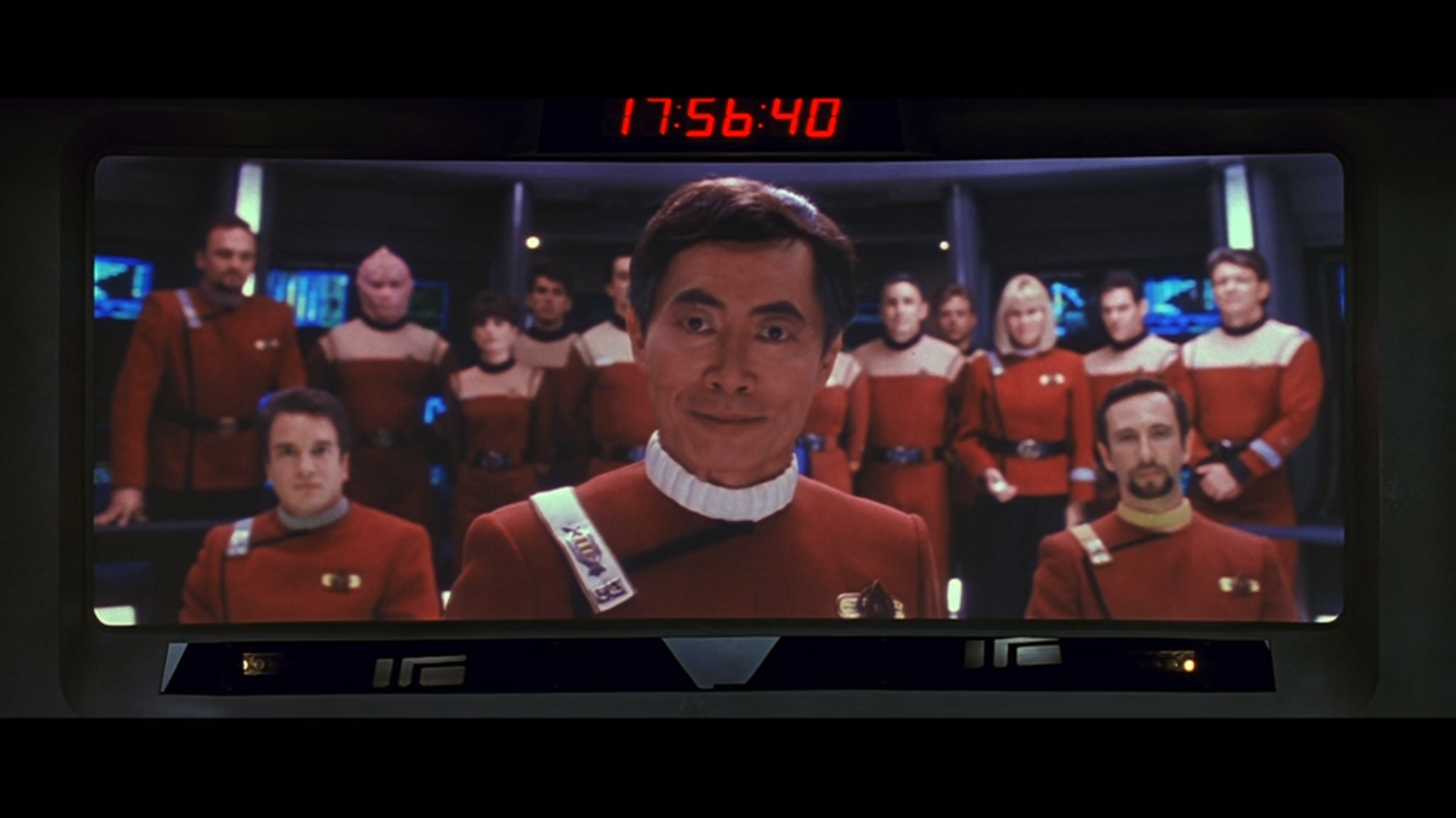 A shot of Captain Sulu on the Enterprise's viewscreen with his crew behind him.