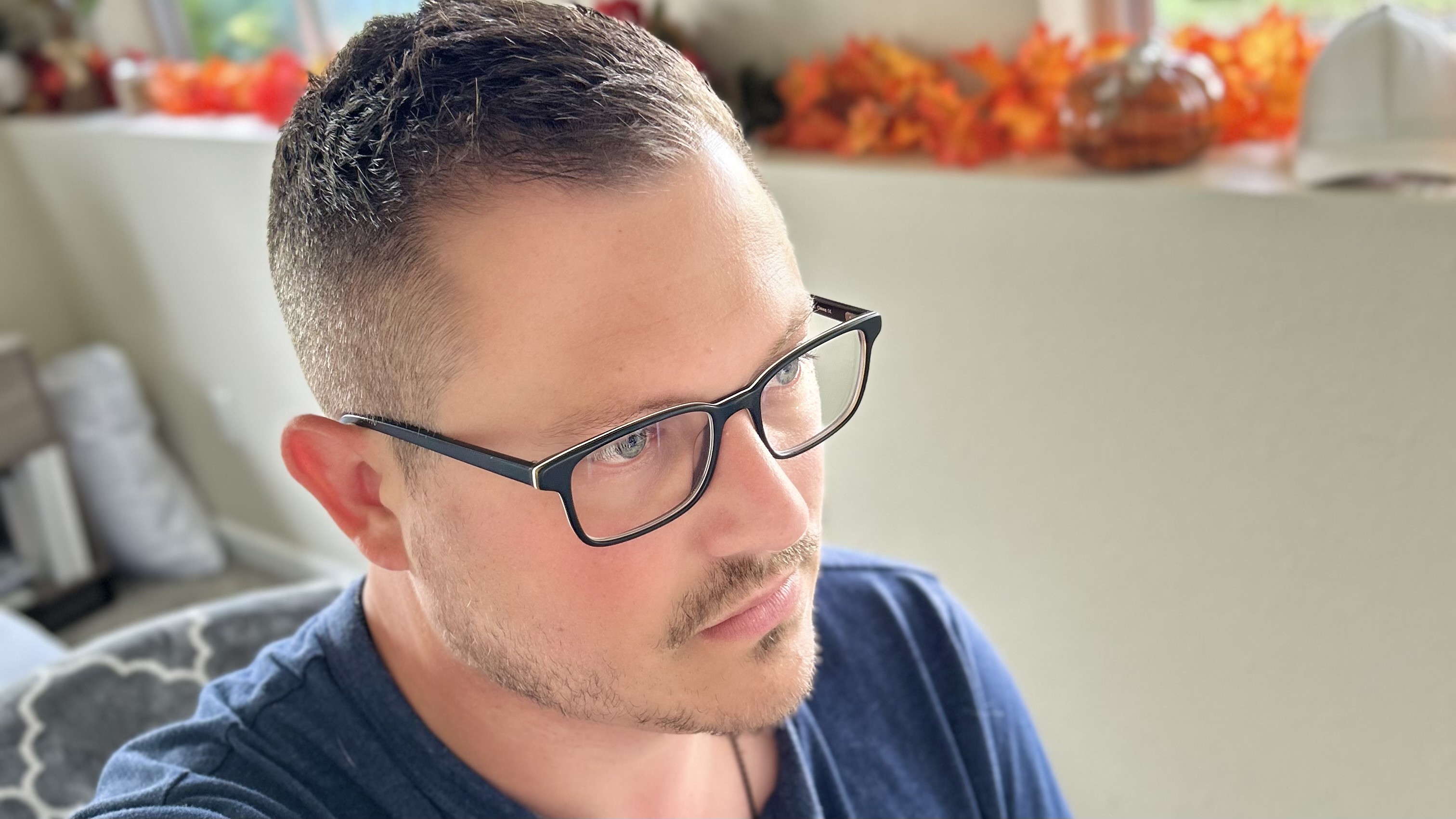 Three quarters profile view of Jake, wearing glasses, sitting at a computer with fall decorations behind him.