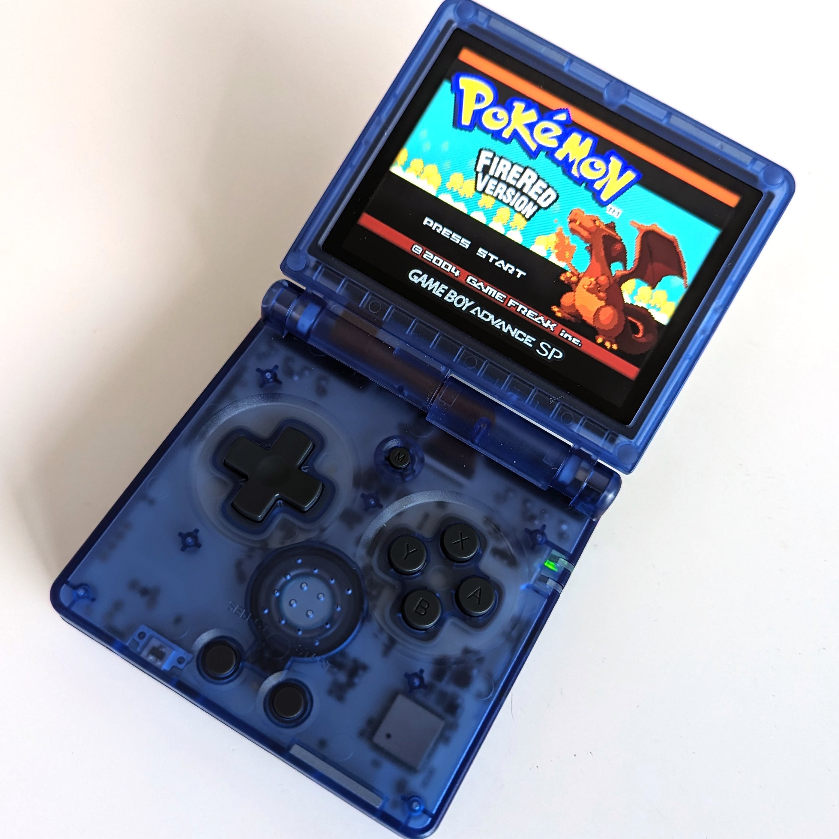 A photograph of an Anbernic RG35XXSP running GBA Pokemon FireRed.