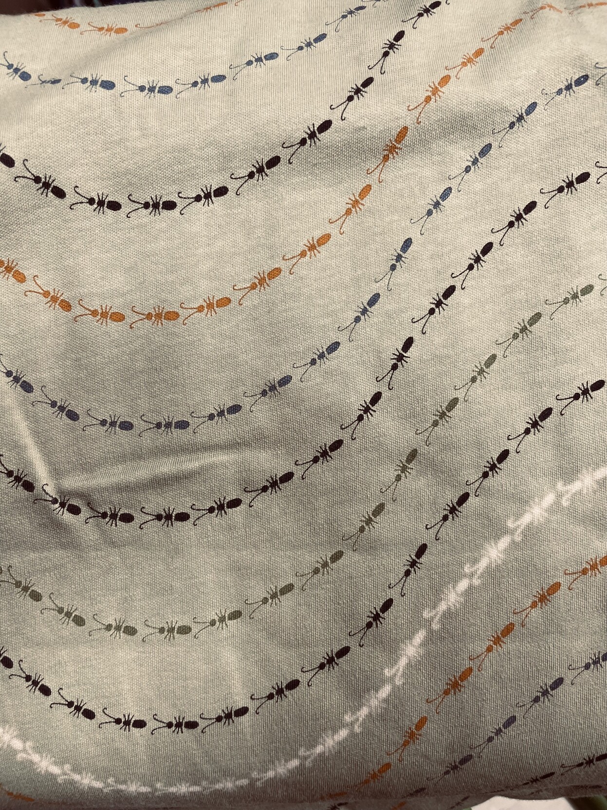 Lightweight knit fabric with a print of insects in wavy lines. Each line of insects is a different colour.