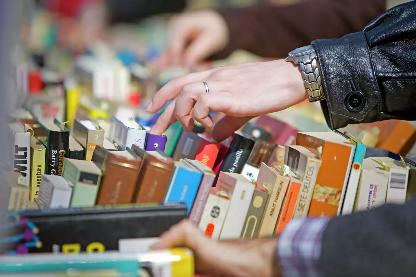 A person rummages through a stack of books. 